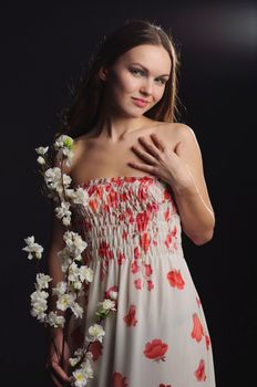 Portrait of a dreamy woman holding sakura in hands. Photograph with little glare of light.