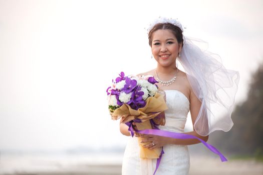 Lovely and beautiful bride with flower bouquet on the beach