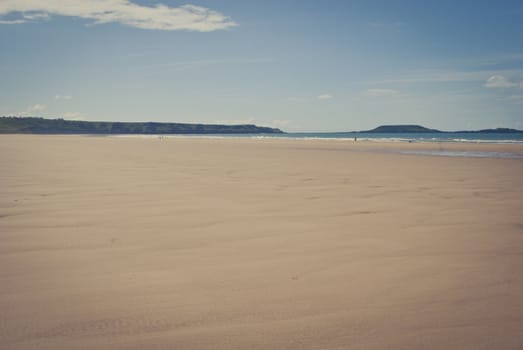 white fluffy clouds and blue skies over empty sandy beach, gower wales