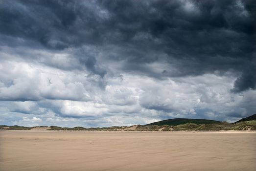 moody skies over deserted yellow sandy beach, gower wales