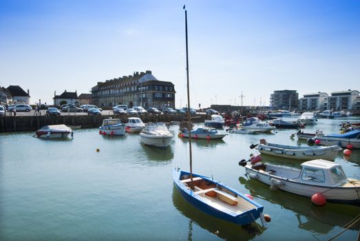 Boats floating in calm harbour, West Bay, Dorest, England with buildings in beackground