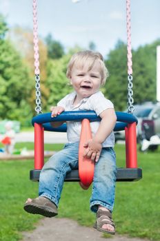 Happy little boy swinging on a swing