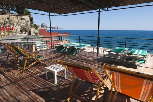 empty deck chairs on terrace, under canopy at beach club capri, italy, looking out to sea