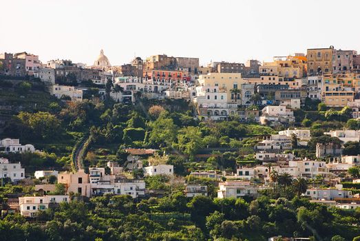 houses stacked close together on big rugged cliffs topped with church, capri italy