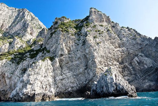 sheer cliffs of capri falling into turqoise mediterannean  sea, italy