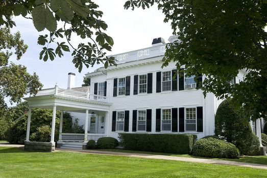 grand white wooden house with porch and large lawn, surrounded by trees, new england, america