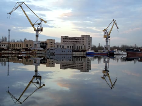 Shipyard view with two cranes reflection in water
