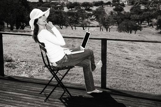 Woman enjoying a beautiful day with a laptop on her home-field