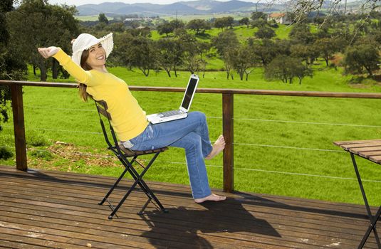 Woman enjoying a beautiful day with a laptop on her home-field