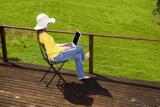 Woman enjoying a beautiful day with a laptop on her home-field