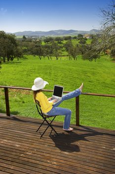 Woman enjoying a beautiful day with a laptop on her home-field