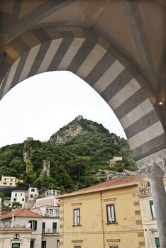 looking through decorative arch to house on top of hill amalfi