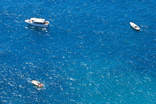 looking down on 3 small boats floating on glistening turqoise sea