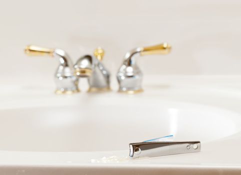 Finger nail clippings on bathroom sink with gold faucets or taps