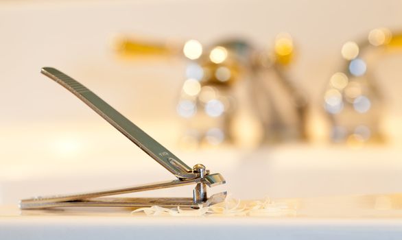 Finger nail clippings on bathroom sink with gold faucets or taps
