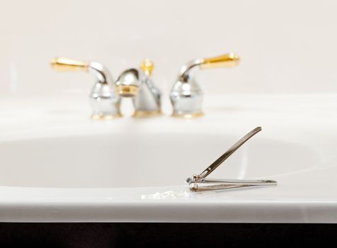 Finger nail clippings on bathroom sink with gold faucets or taps