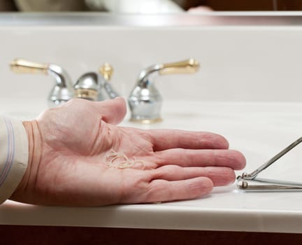 Finger nail clippings in palm of hand on bathroom sink