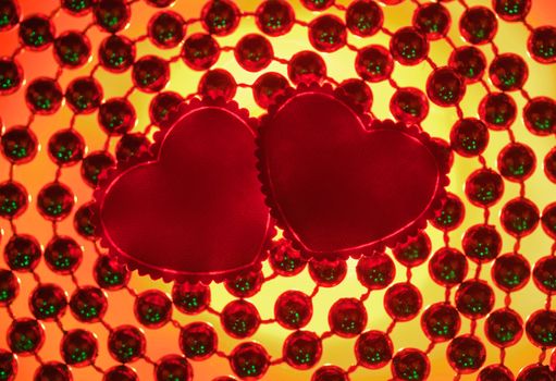 Two silk red hearts against a beads background