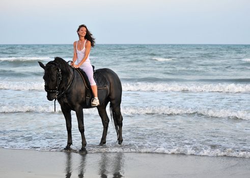young woman an her black stallion in the sea