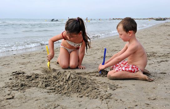 young children are playing on the beach