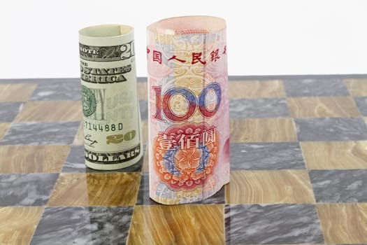 Dollar and yuan currency stand on marble chess board; opponents in financial game; political or policy conflict in game of life; 