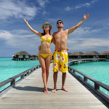 Couple on a tropical beach jetty at Maldives