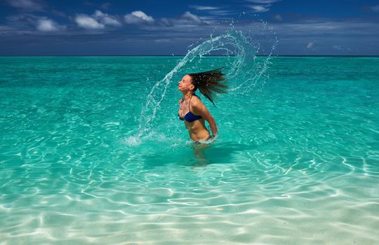 Woman splashing water with her hair in the ocean