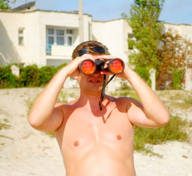 A man with binoculars on the beach