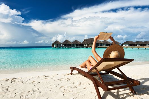 Young woman reading a book at the beach