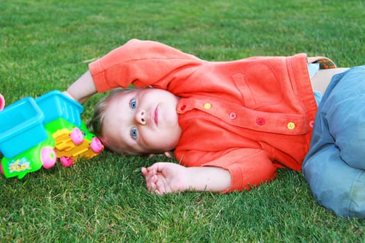 Baby lying on the grass with a toy