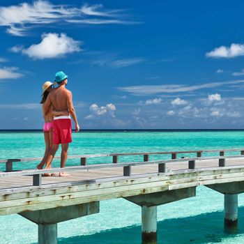 Couple on a tropical beach jetty at Maldives