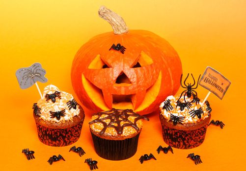 Halloween cupcakes with decoration over orange background