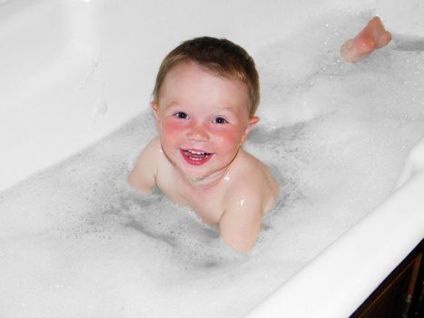 Joyful baby is bathed in a bathtub