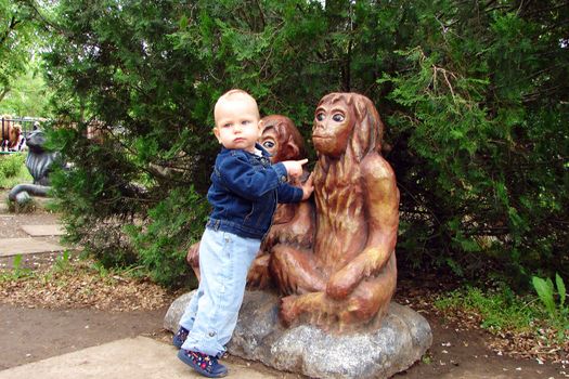 Babe in the city park next to the statues of monkeys