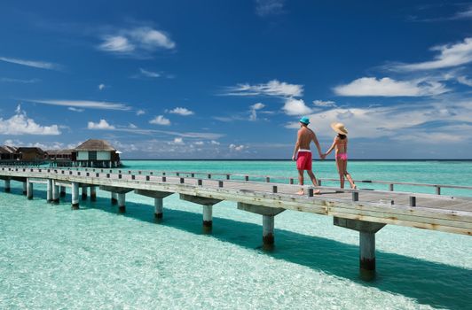 Couple on a tropical beach jetty at Maldives