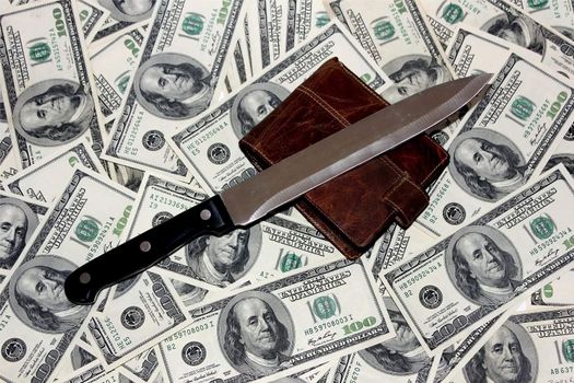 knife and a purse lying on the 100 dollar bills