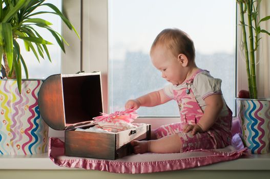 Girl in the pink overall sits on sill