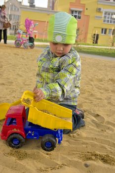 baby boy playing with toy auto in sand box