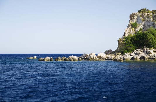 stony coast and waves of dark blue sea in a canicular day