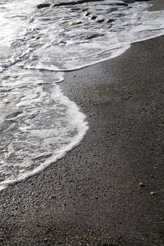 Sea foam formed from waves rolling on coast