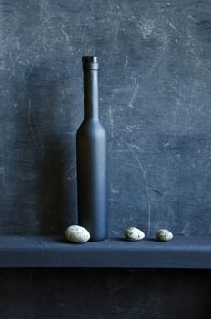 black still-life with bottle and three bird eggs