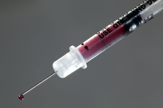 Macro of a drop of blood on the end of a hypodermic syringe needle