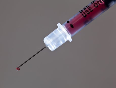 Macro of a drop of blood on the end of a hypodermic syringe needle