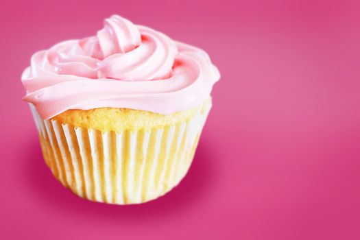 Vanilla cupcake with pink frosting over same color background