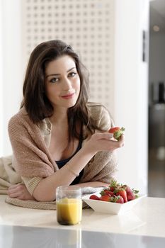 Attractive young woman enjoying a fresh fruit breakfast at home.