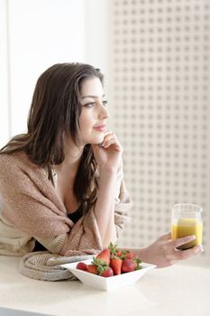 Attractive young woman enjoying a fresh fruit breakfast at home.