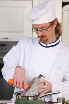 Young chef with carrot, preparing lunch in kitchen