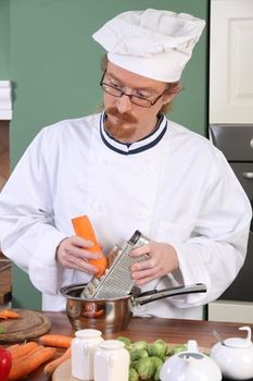 Young chef with carrot, preparing lunch in kitchen 