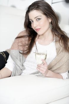 Attractive young woman enjoying a glass of wine on her sofa.