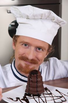 Young chef with piece of cake with chocolate sauce 